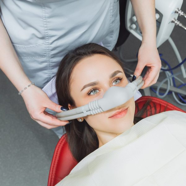 Dentist,Puts,Inhalation,Sedative,Mask,On,His,Patient.